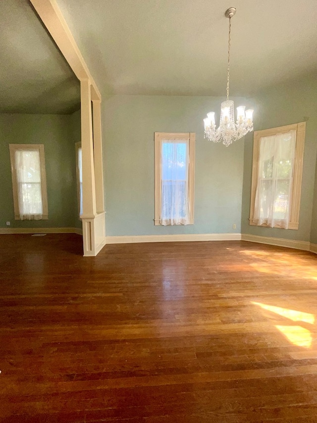 empty room with hardwood / wood-style floors and a notable chandelier