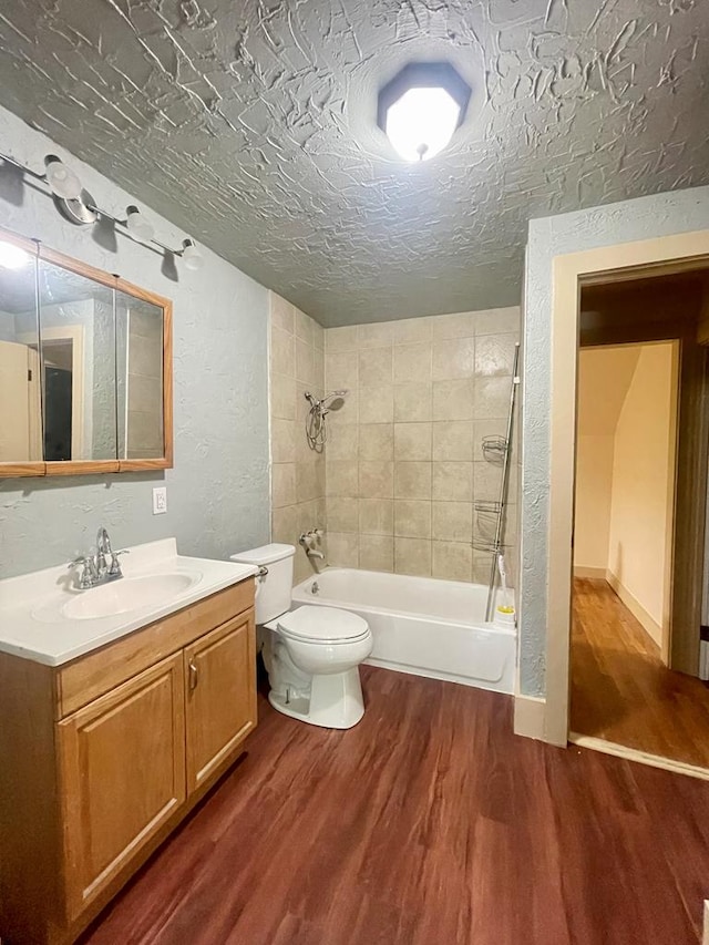 full bathroom featuring hardwood / wood-style flooring, tiled shower / bath combo, toilet, and a textured ceiling