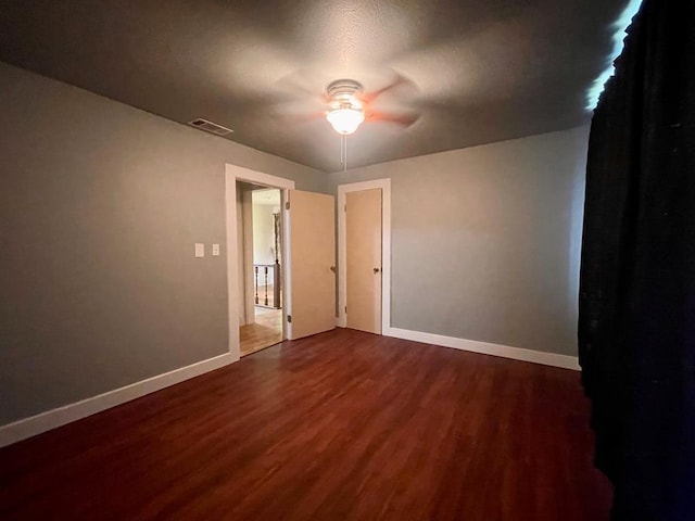 empty room featuring ceiling fan and dark wood-type flooring