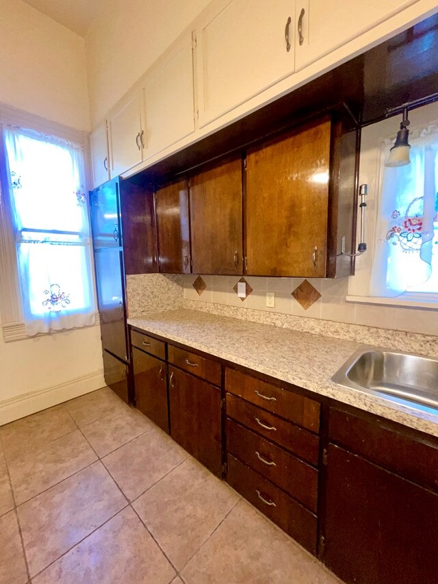 kitchen with dark brown cabinetry, white cabinetry, sink, hanging light fixtures, and light tile patterned floors