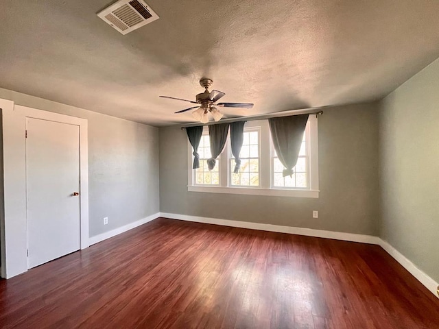 spare room featuring a textured ceiling, ceiling fan, and dark wood-type flooring