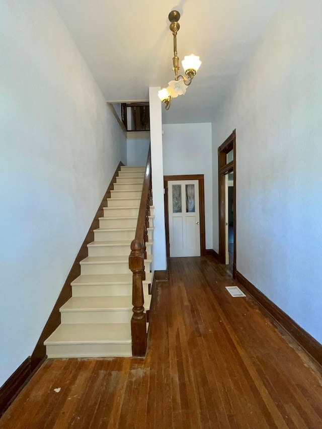 stairs featuring wood-type flooring and a notable chandelier