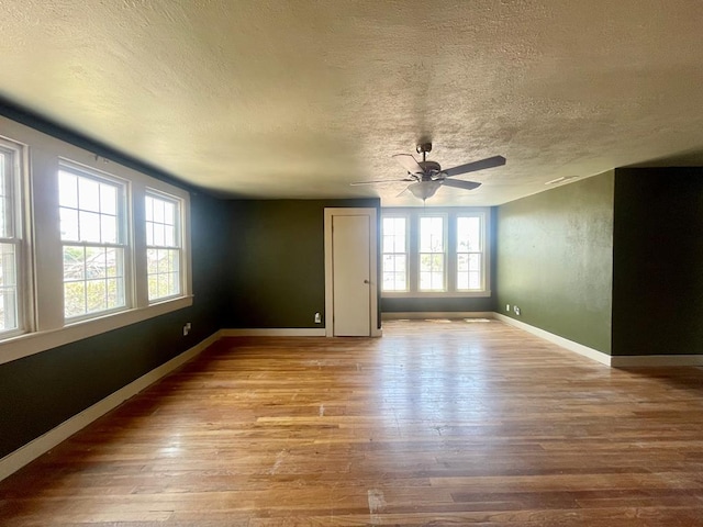 spare room with a textured ceiling, light wood-type flooring, and a wealth of natural light