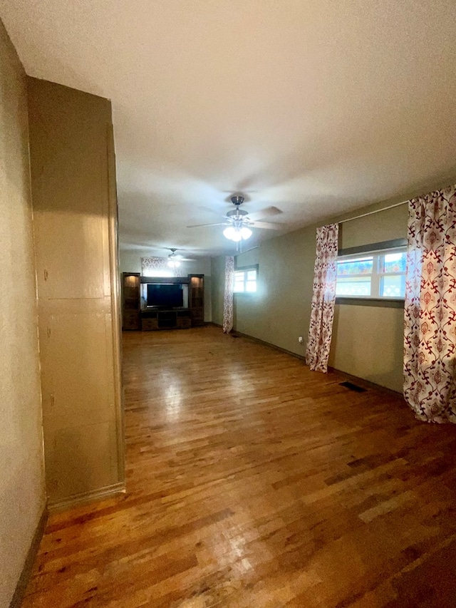 unfurnished living room featuring hardwood / wood-style floors, plenty of natural light, and ceiling fan