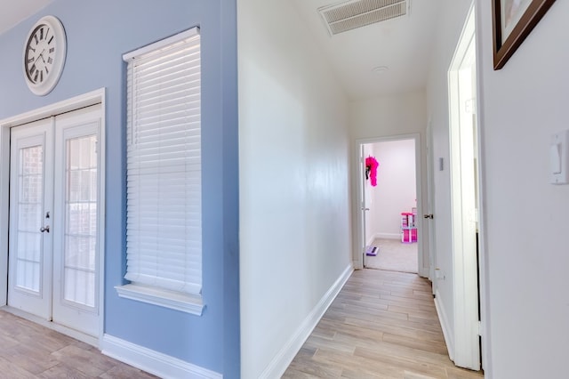 hall featuring baseboards, visible vents, french doors, and light wood finished floors