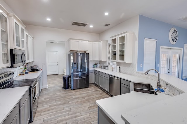 kitchen featuring stainless steel appliances, a sink, visible vents, and light wood-style floors