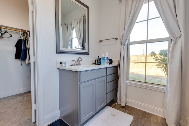 bathroom featuring baseboards, wood finished floors, and vanity