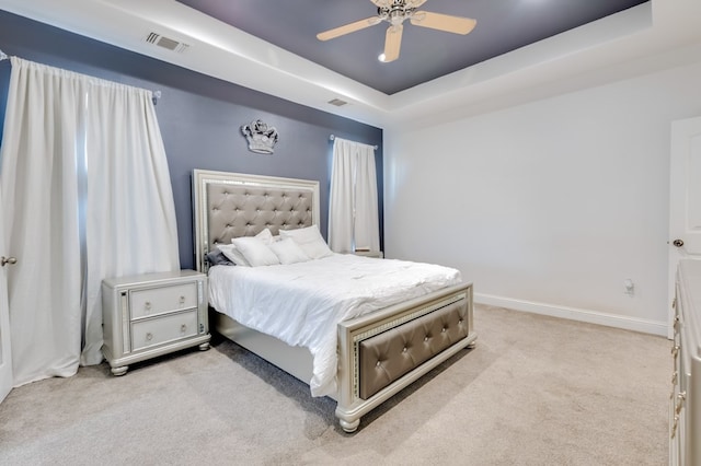 bedroom featuring baseboards, a tray ceiling, visible vents, and light colored carpet