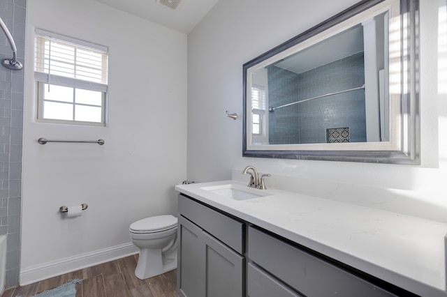 full bath with visible vents, toilet, vanity, wood finished floors, and baseboards