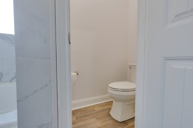 bathroom with toilet, baseboards, and wood finished floors