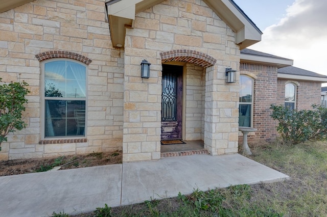 doorway to property featuring stone siding and brick siding