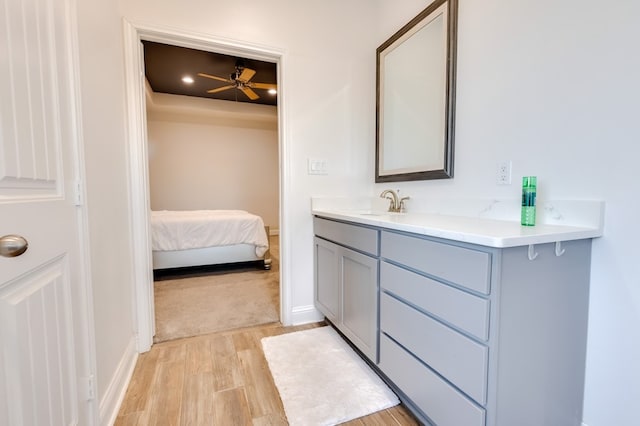 ensuite bathroom featuring connected bathroom, wood finished floors, vanity, and baseboards