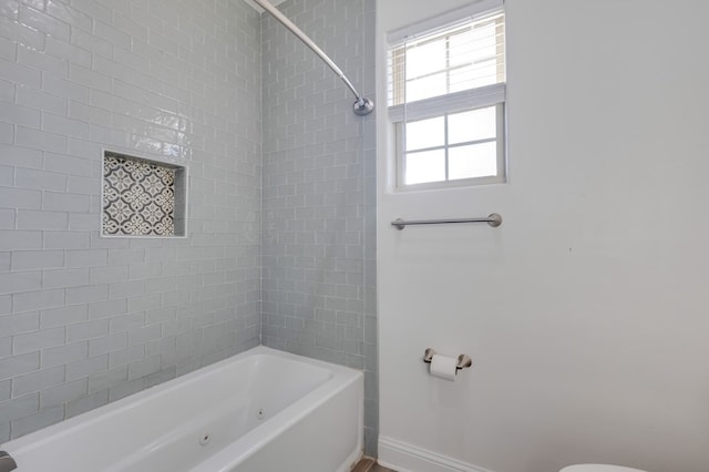 bathroom with a combined bath / shower with jetted tub and baseboards