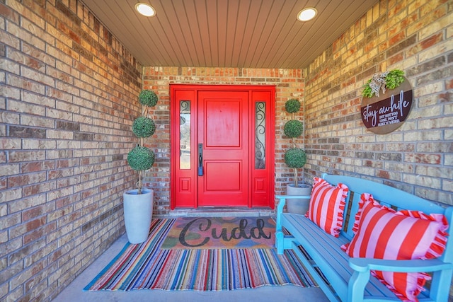 doorway to property with covered porch and brick siding