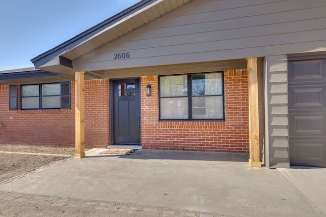 view of exterior entry with a garage and brick siding