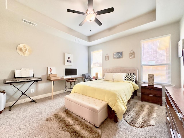 carpeted bedroom with baseboards, visible vents, ceiling fan, and a tray ceiling