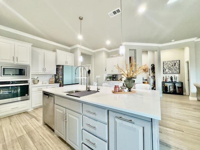 kitchen with appliances with stainless steel finishes, visible vents, a sink, and white cabinetry