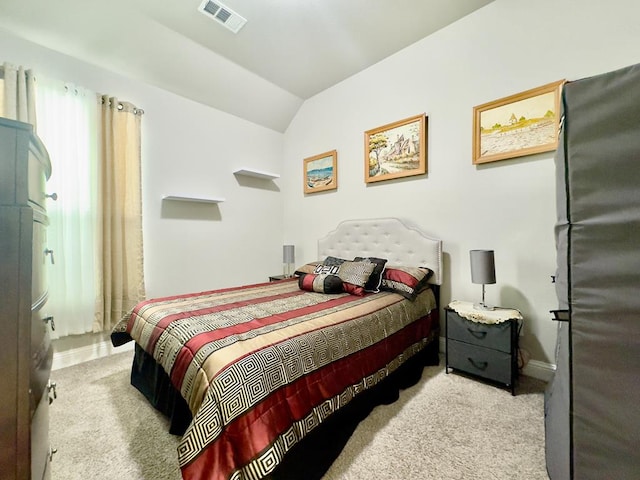 bedroom featuring visible vents, vaulted ceiling, carpet flooring, and freestanding refrigerator