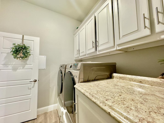 washroom with baseboards, cabinet space, light wood finished floors, and washing machine and clothes dryer