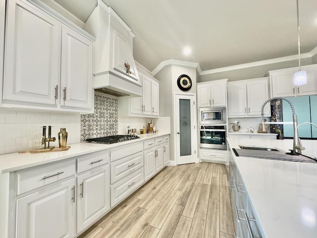 kitchen with stainless steel appliances, light countertops, decorative backsplash, white cabinets, and premium range hood