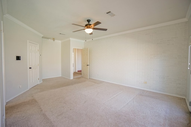 empty room featuring ceiling fan, brick wall, crown molding, and light carpet