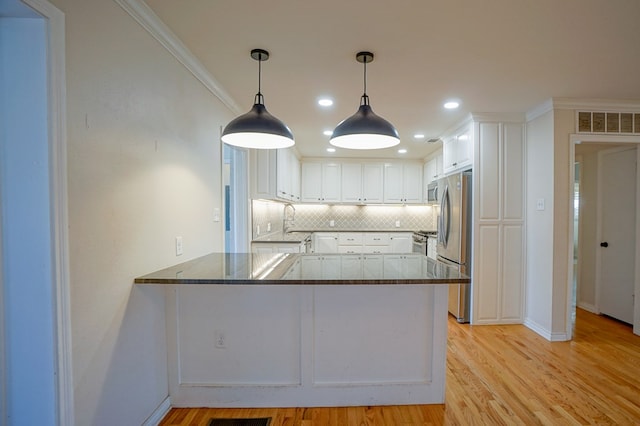 kitchen with white cabinetry, kitchen peninsula, sink, crown molding, and decorative backsplash