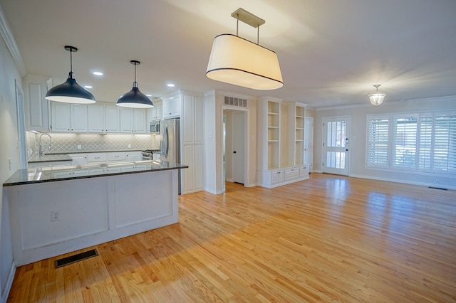 kitchen featuring sink, white cabinets, crown molding, and hanging light fixtures