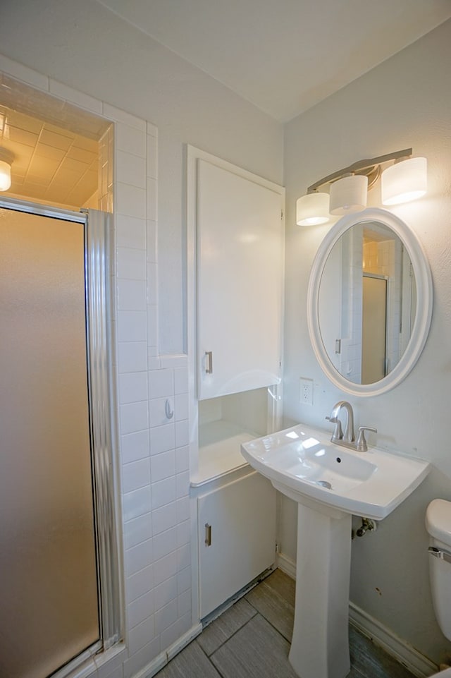 bathroom featuring hardwood / wood-style flooring, toilet, and a shower with shower door