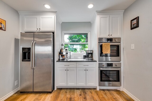 2603 Hughes St, Midland, TX 79705 - kitchen with appliances with stainless steel finishes, white cabinetry, light wood-type flooring, dark countertops, and recessed lighting