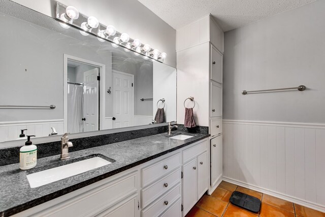 2603 Hughes St, Midland, TX 79705 - full bath with wainscoting, double vanity, a textured ceiling, tile patterned floors, and a shower with shower curtain