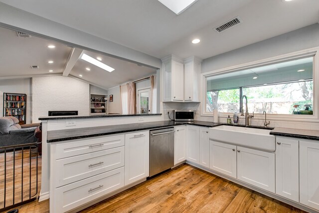 2603 Hughes St, Midland, TX 79705 - kitchen with appliances with stainless steel finishes, open floor plan, white cabinetry, light wood-type flooring, and a peninsula