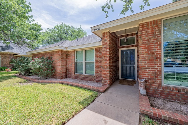 entrance to property with a yard and brick siding