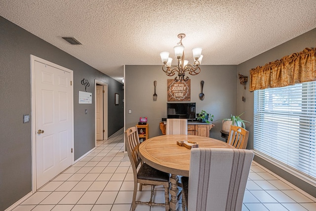 dining space with a chandelier, light tile patterned floors, and a textured ceiling