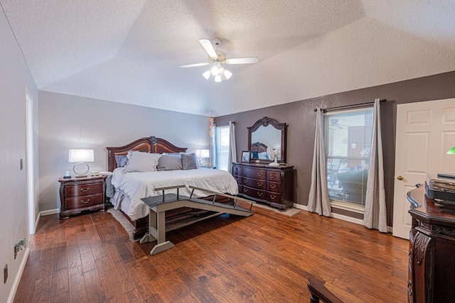 bedroom with vaulted ceiling, wood finished floors, a textured ceiling, baseboards, and ceiling fan