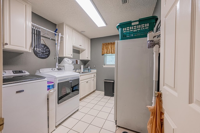 kitchen featuring separate washer and dryer, freestanding refrigerator, light tile patterned flooring, white cabinets, and a textured ceiling