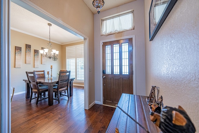 entrance foyer featuring a chandelier, dark wood finished floors, crown molding, baseboards, and a textured wall