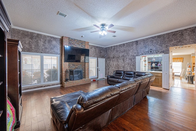 living area with a ceiling fan, wood-type flooring, plenty of natural light, crown molding, and a fireplace