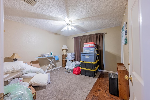 bedroom with a textured ceiling, baseboards, wood finished floors, and a ceiling fan