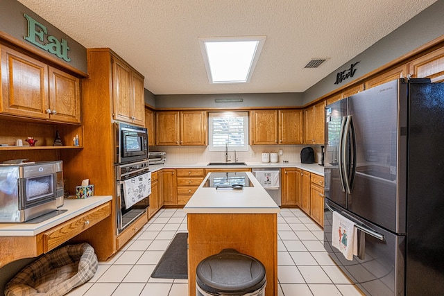 kitchen with black appliances, a sink, light countertops, brown cabinetry, and a textured ceiling