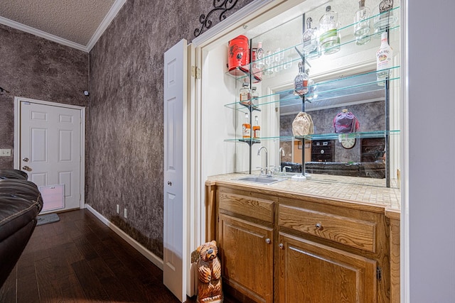bathroom with a sink, crown molding, wood finished floors, baseboards, and a textured ceiling
