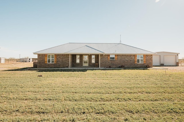 single story home featuring a garage, an outbuilding, and a front lawn