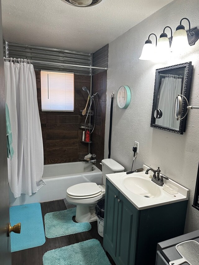 full bathroom with vanity, a textured ceiling, shower / bath combo with shower curtain, hardwood / wood-style flooring, and toilet