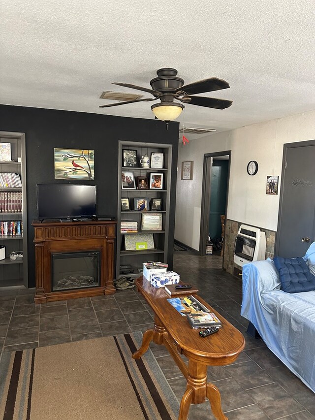 living room featuring dark tile patterned flooring, ceiling fan, a textured ceiling, and heating unit