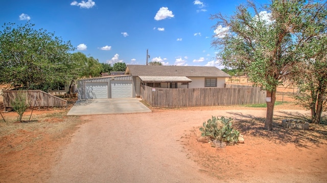 ranch-style home featuring a garage, dirt driveway, and fence