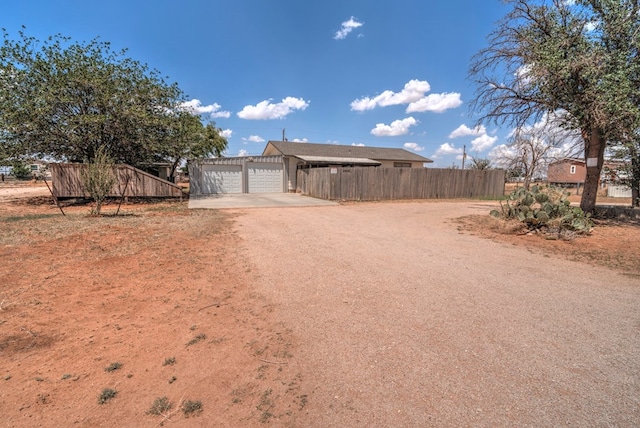 view of yard with fence, driveway, a carport, and a garage