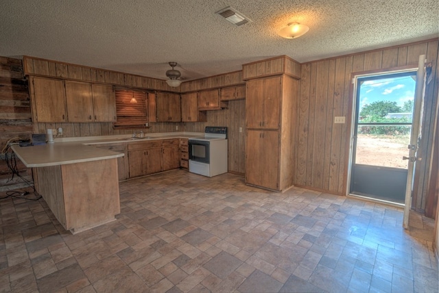 kitchen featuring a peninsula, wood walls, range with electric cooktop, and visible vents