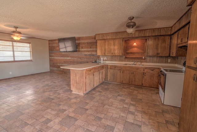 kitchen with a peninsula, white range with electric cooktop, ceiling fan, wooden walls, and light countertops