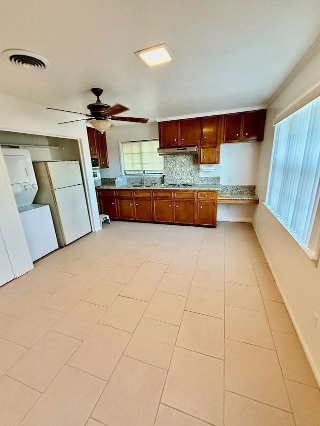 kitchen with stacked washer / drying machine, white refrigerator, ceiling fan, light tile patterned floors, and decorative backsplash