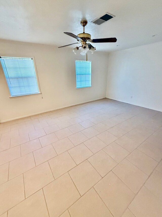 tiled spare room featuring ceiling fan