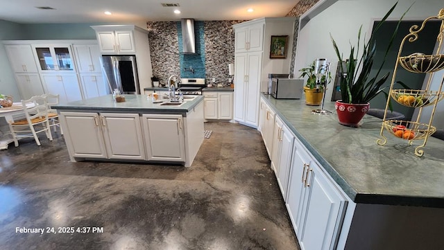24501 S County Rd 1210, Midland, TX 79706 - kitchen with wall chimney exhaust hood, stainless steel appliances, a center island with sink, concrete floors, and white cabinets